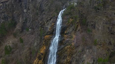 Nahaufnahme-Eines-Atemberaubenden-Wasserfalls-Per-Drohne,-Der-Eine-Felsige-Klippe-Hinabstürzt-Und-Von-Grünen-Bäumen-Umgeben-Ist