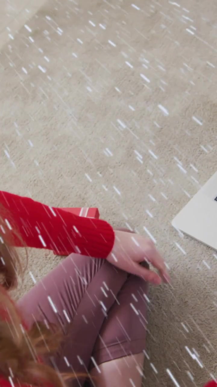 Animation of snow falling over smiling woman in santa hat on laptop video call with her family