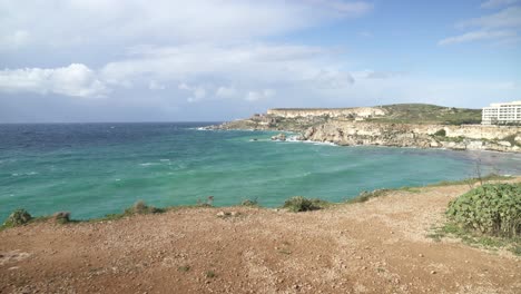 Día-Soleado-En-La-Bahía-De-Ghajn-Tuffieha-Con-Olas-Del-Mar-Mediterráneo-Rodando-Hacia-La-Orilla