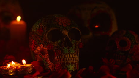 close up on still life of decorated skulls surrounded by candles and flower petals celebrating mexican holiday of dia de muertos or day of the dead 3