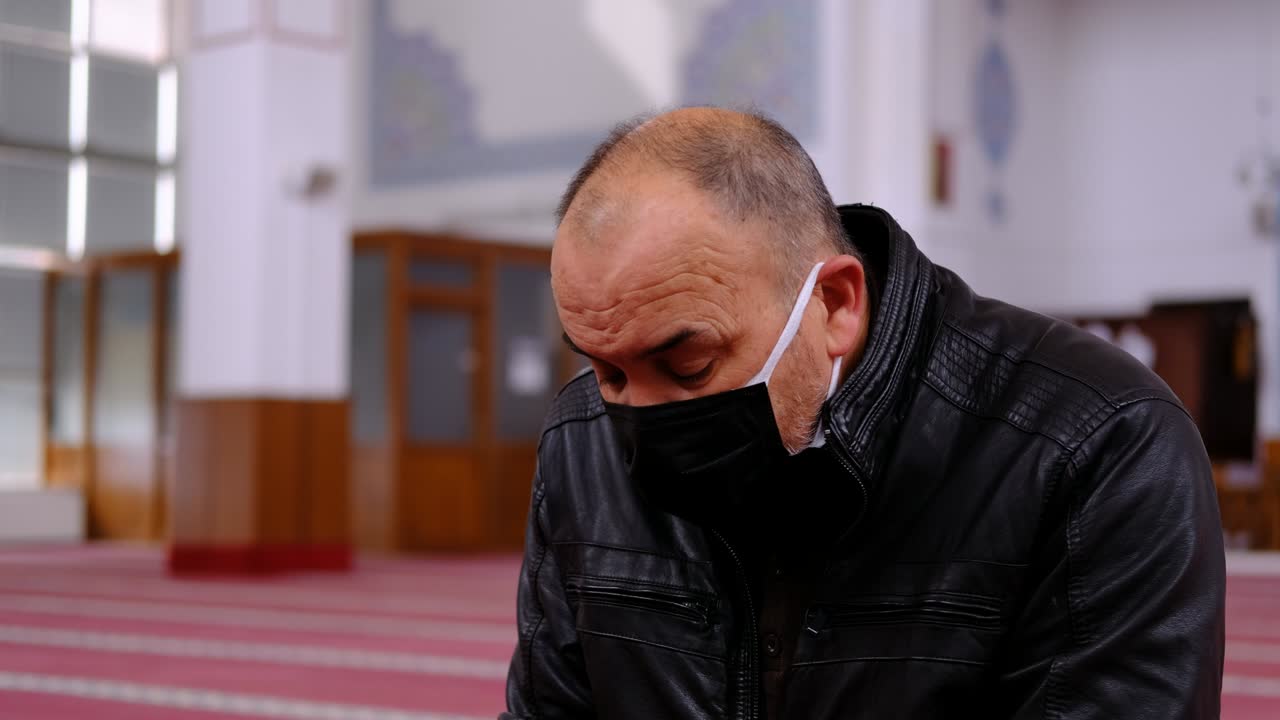 Camide başını çeviren maskeli yaşlı adam