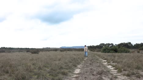 a bushman runs with his border collie dog in the australian desert down a remote dirt track