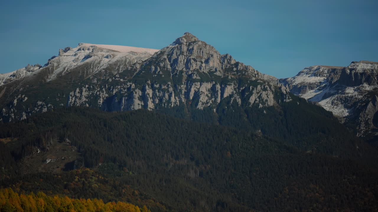 Panoramaoptagelse af en høj sneklædt bjergkam, klar solrig varm dag