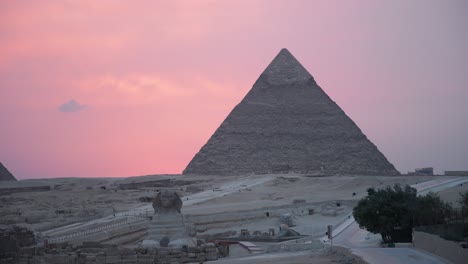 la gran pirámide y la esfinge con una cálida puesta de sol detrás de ellos
