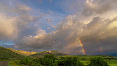timelapse, clouds and rainbow over pristine landscape in summer season
