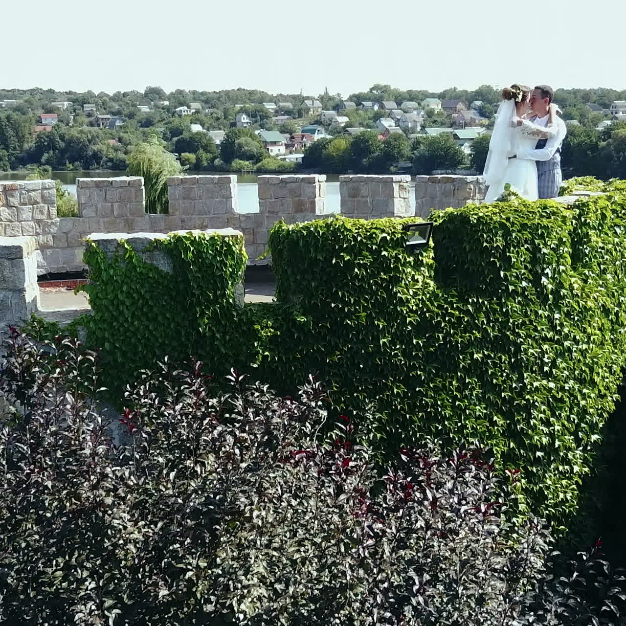 Bella e romantica coppia di novelli sposi che si abbracciano in un vecchio castello. Vista aerea. Video quadrato.