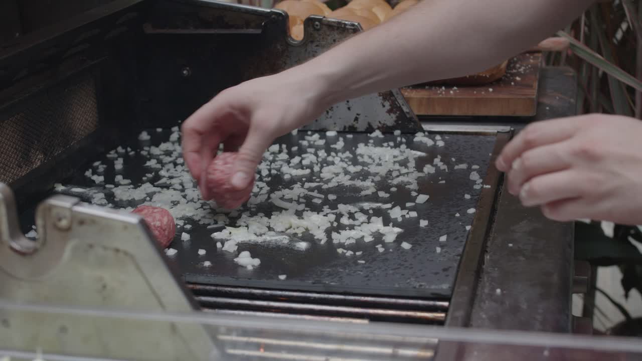 요리사는 쇠고기 미트볼을 뜨거운 철판 위에 올려 놓습니다.