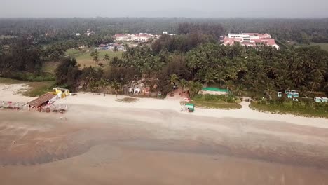 a drone shot over a beautiful sea heading towards the trees, goa, india