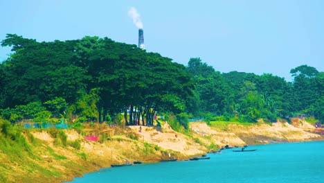 erosión fluvial y emisión de humo de la chimenea de la fábrica por la orilla del río en bangladesh - amplia toma estática