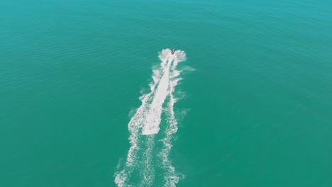 fast jet ski across the surface of the water with waves crashing