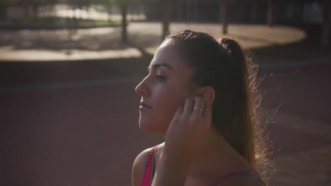 Mujer-Caucásica-Poniéndose-Auriculares-En-Un-Parque