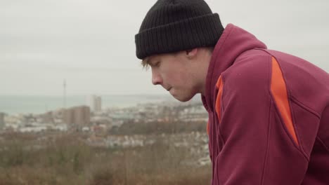 White-man-in-Hoodie-and-Hat-looks-over-Brighton,-Seaside-City