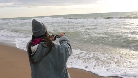 chica grabando video en la playa al atardecer