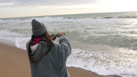 girl recording video on beach at sunset