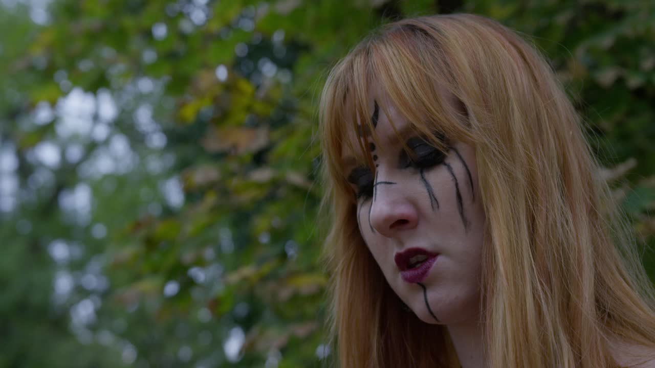 Beautiful Witch smiling in an evil way to the camera and turning around in the cemetery, slow motion Close up