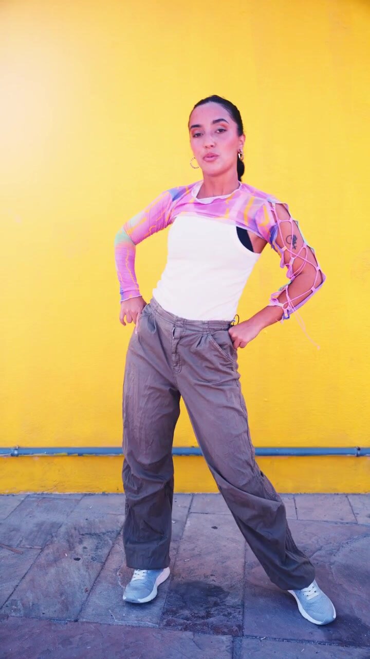 Young Woman Dancing in Front of a Bright Yellow Wall