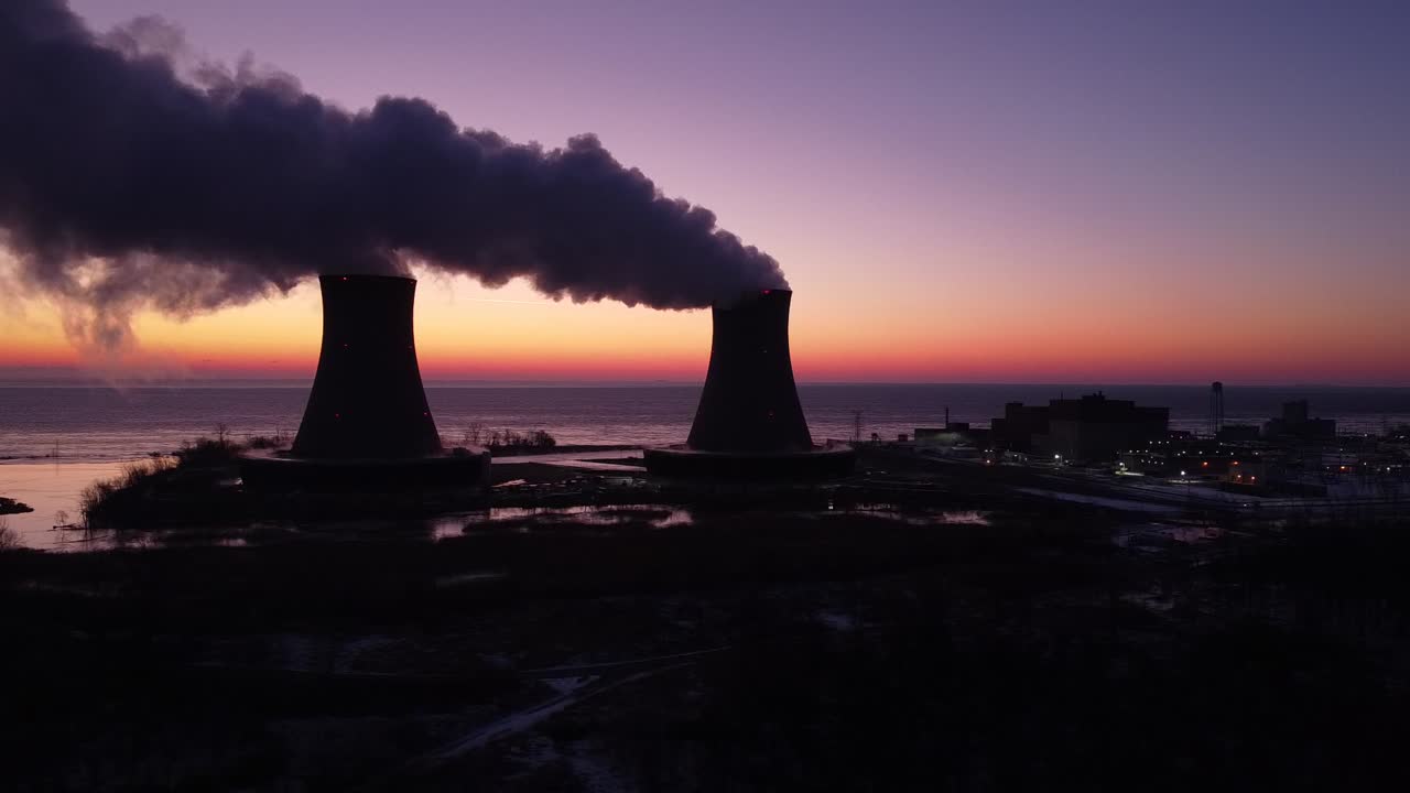 dolly izquierda - torres de enfriamiento de la planta de energía nuclear de aviones no tripulados aéreos al amanecer atardecer con invierno de humo de vapor