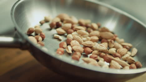 closeup mix of nuts tossing on frying pan in slow motion.