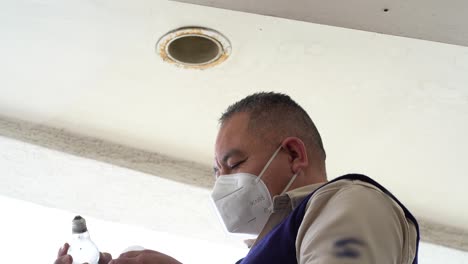 reparador latino cambiando bombilla. hombre hispano cambiando bombilla