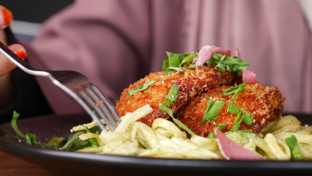 mujer comiendo pasta de pesto con pollo frito