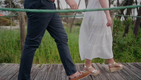 couple walking on a wooden boardwalk in a natural, outdoor setting