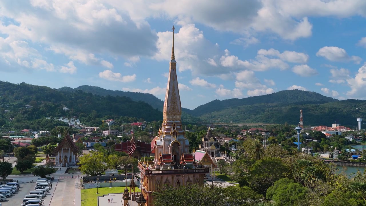 Chùa Wat Chalong dưới những đám mây ấn tượng ở Phuket, quay từ trên cao nghiêng xuống không gian bãi cỏ trống.