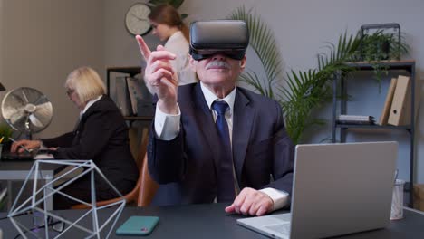 A senior businessman wearing a VR headset points his finger in an office
