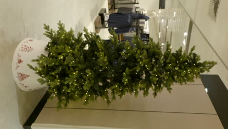 árbol de navidad brillante en el centro comercial local, vista de movimiento vertical
