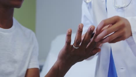 Close-up-of-African-american-female-doctor-checking-sugar-level-of-male-patient-in-hospital-ward