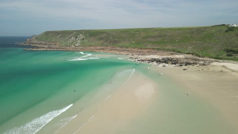 gwenver beach turquoise seaside in cornwall with pristine beach, aerial drone panning shot