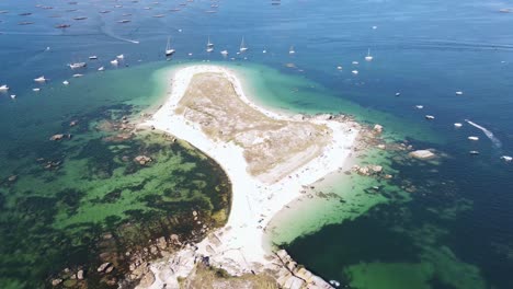 aerial drone video of sandy island and fishing boats in green clear water with rocks in galicia, pontevedra, spain