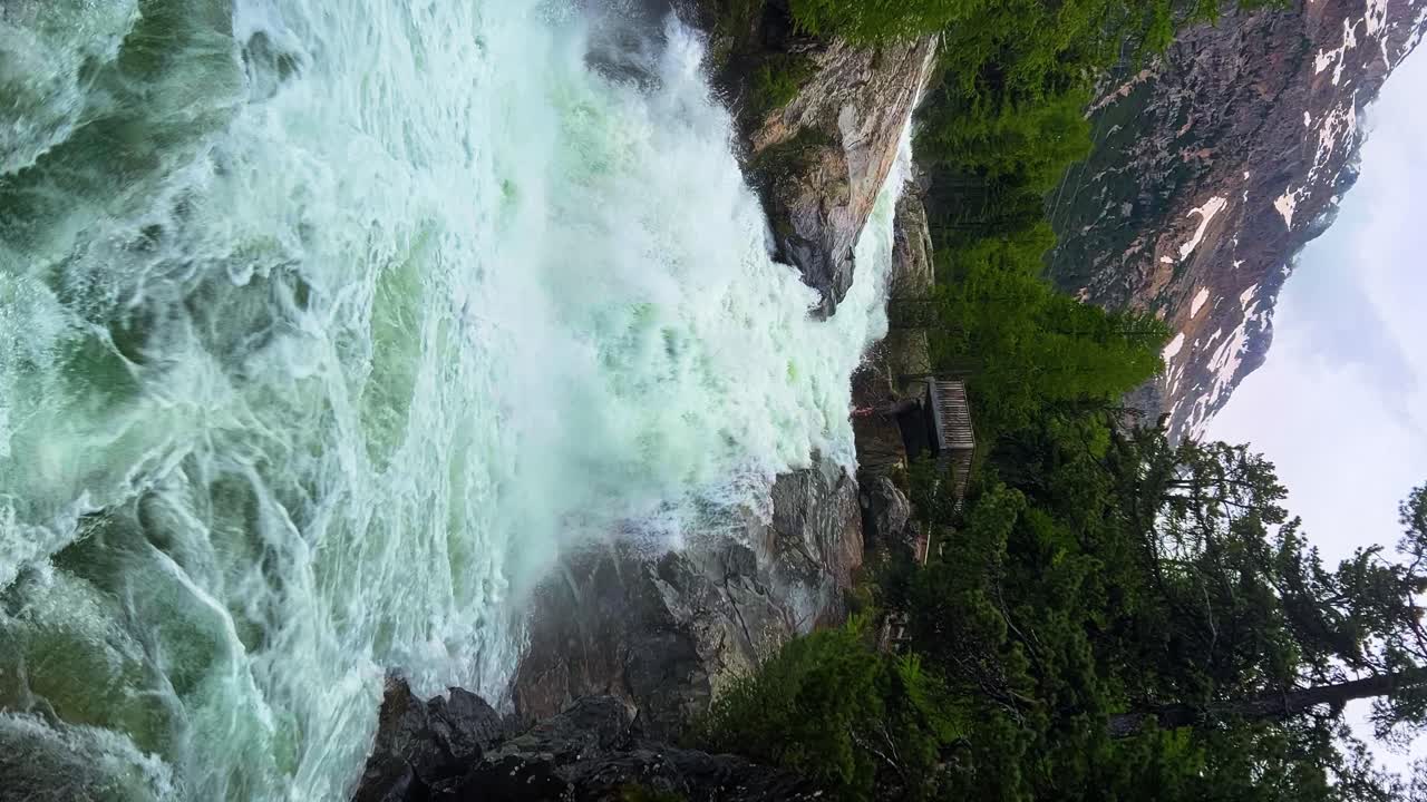 fotografía vertical de una cascada salvaje con los alpes suizos en el fondo en suiza