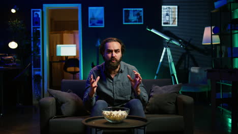 dejected man at home on couch watching sports match on live broadcast