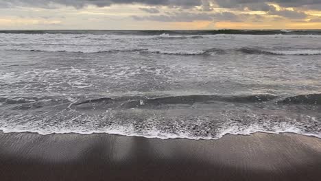 ocean waves washing the shore on a gloomy day in indonesia - wide shot