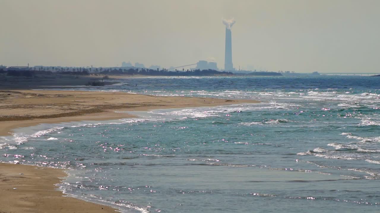 Mediterranean beach with a power plant in the background