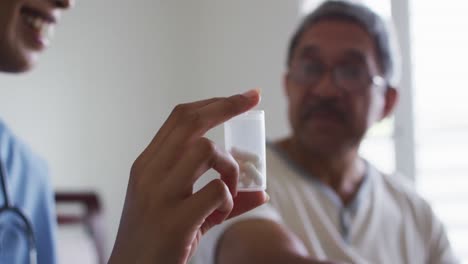 Senior-mixed-race-man-with-female-doctor-talking-and-holding-pills