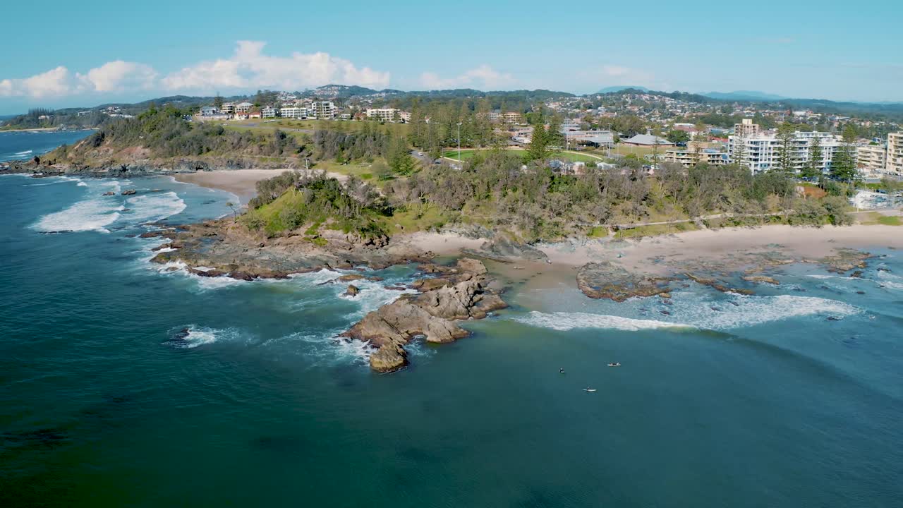 Aerial view of tropical beachfront with elevated residences and surf activity along the coast, showcasing the vibrant landscape and ocean waves from Echo Beach, Bali