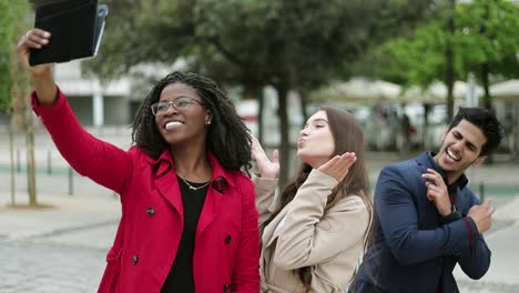 two women and man making selfie outside, posing, smiling