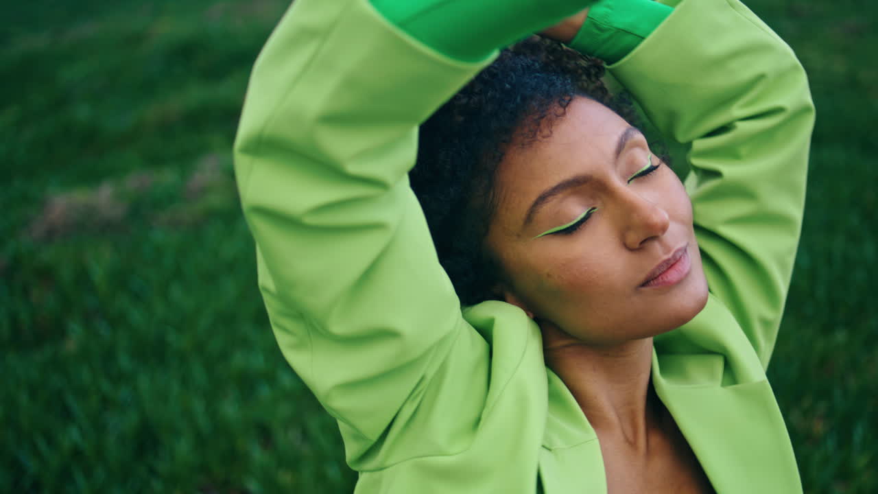 Rilassata signora africana che balla sensualmente nella natura con gli occhi chiusi, primo piano.