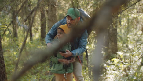 father and son navigating in woods with smartphone