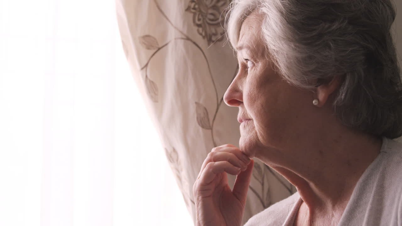 Thoughtful senior woman looking through window