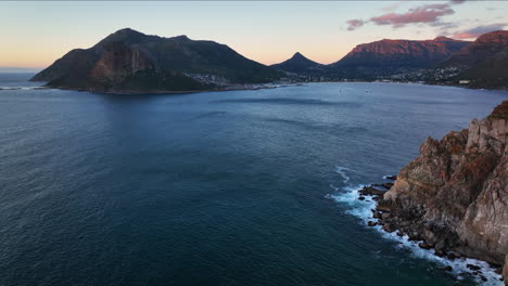 Chapman-Peak-Südafrika-Sonnenuntergang-Fahrt-Luftaufnahme-Filmische-Drohne-Hout-Bay-Marina-Kapstadt-Fish-Hoek-Gute-Hoffnung-Tafelberg-Wellen-Krachen-Zerklüftete-Küste-Aqua-Tiefblaues-Wasser-Grün-Sommer-Vorwärtsschwenk