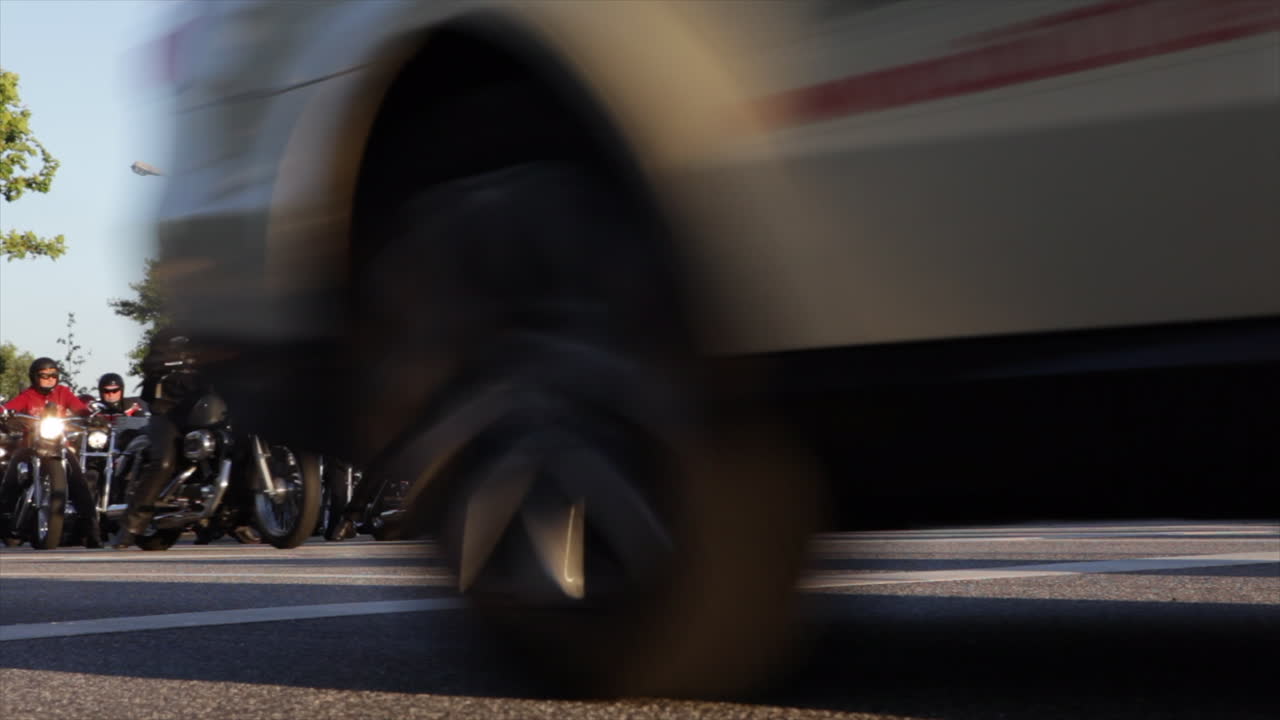 Low angle shot of otorbikes starting at a crossing on a big street at sunset