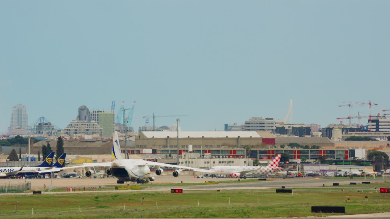 都市のスカイラインを背景に、混雑した空港をタキシングする大型貨物機