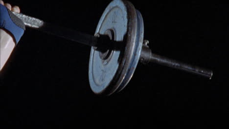 a young man exercises by lifting a heavy barbell above his head