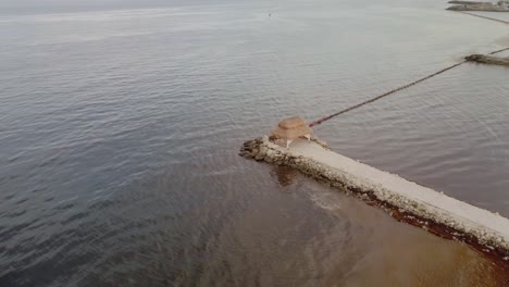 AERIAL---A-cabana-in-rocky-pier-in-Cancun,-Mexico,-high-angle-spinning-shot