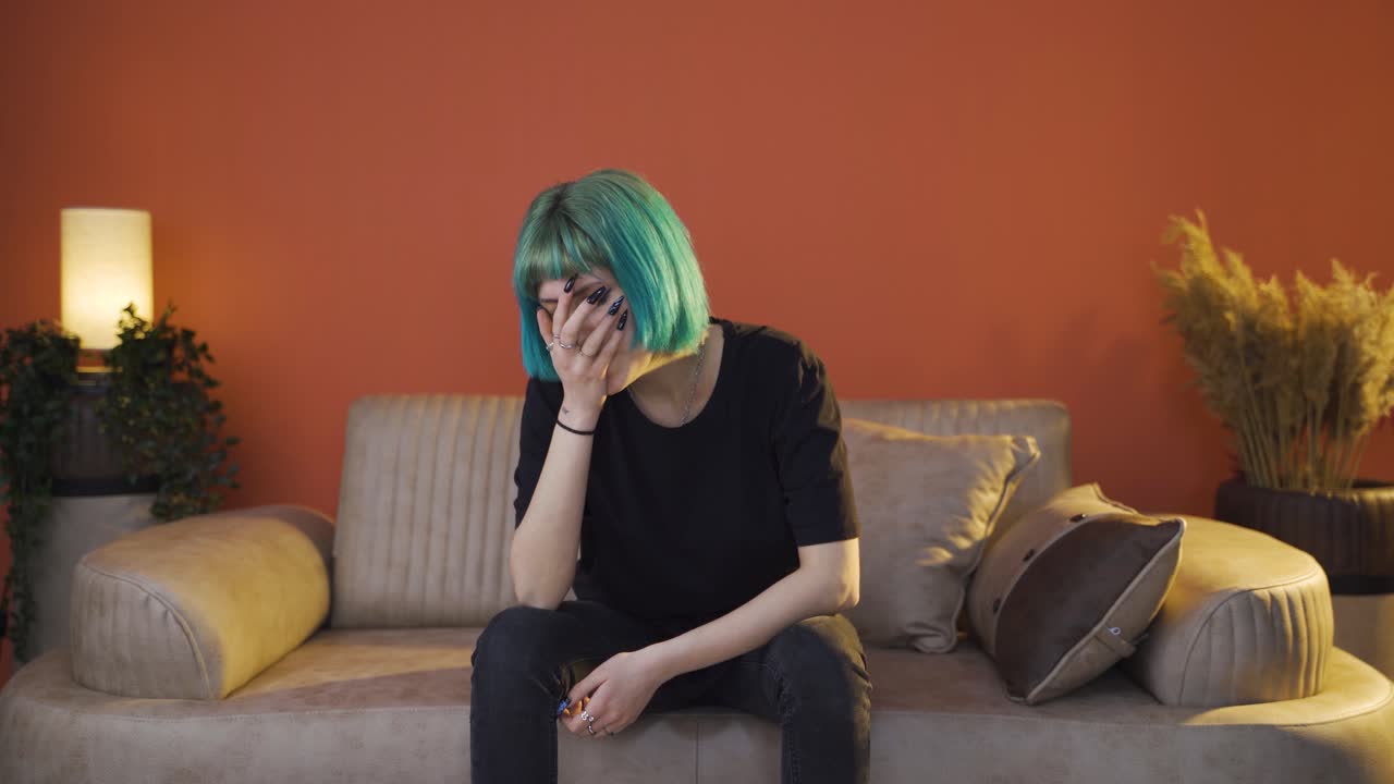 Depressed young woman covering her face with her hand.