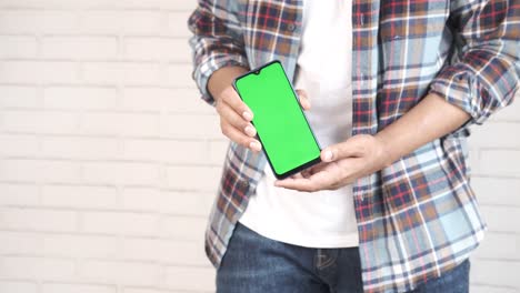 hombre sosteniendo un teléfono inteligente con una pantalla verde