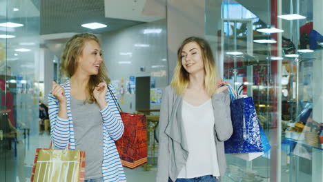Zwei-Attraktive-Frauen-Gehen-Mit-Einkaufstüten-Durch-Das-Einkaufszentrum-Und-Sprechen-HD-Video