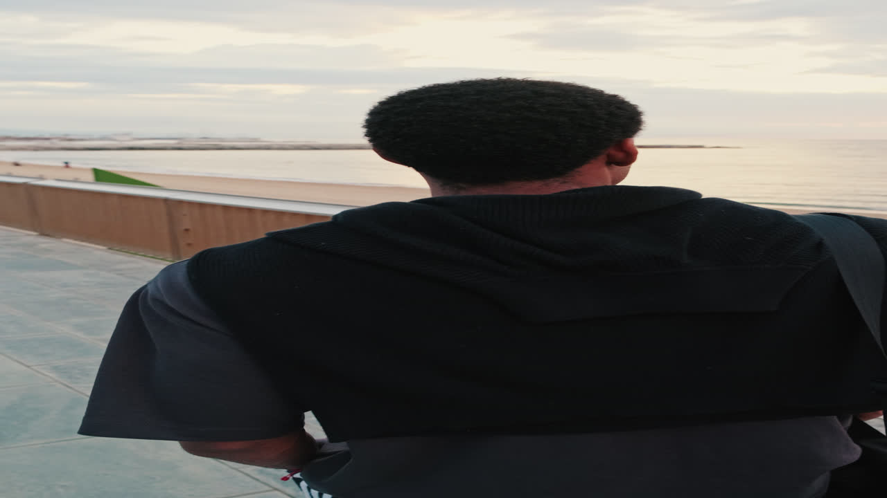 Man Standing on Promenade Looking Out at the Beach and Sea